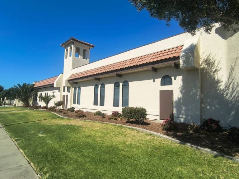 Freshly painted beige stucco exterior of a Spanish-style commercial building with terracotta roof tiles under a clear blue sky