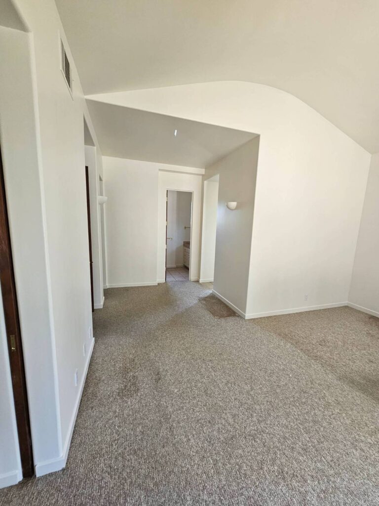 An empty room with freshly painted white walls and light beige carpet, showcasing a clean interior ready for residential painting services.