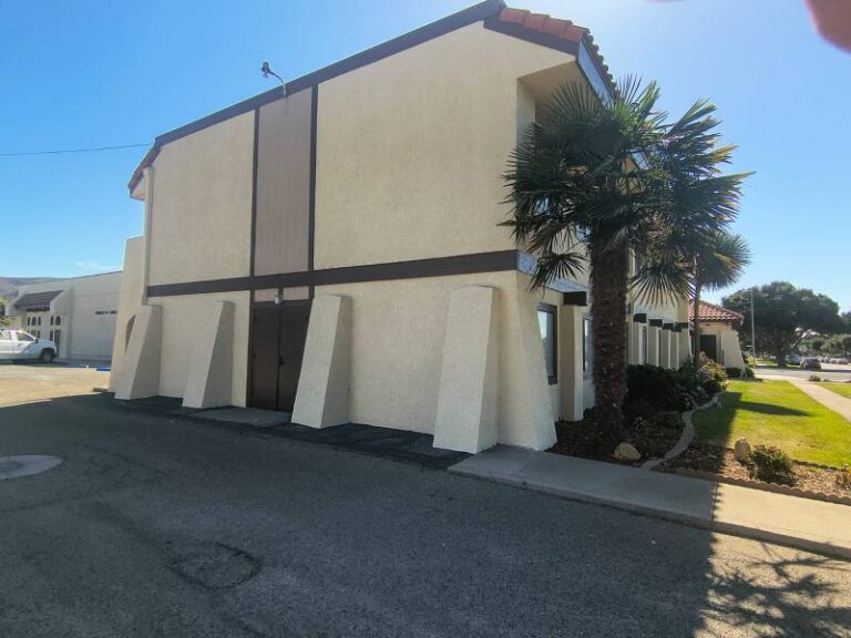 Exterior view of a multi-story commercial building featuring freshly painted beige stucco walls and dark brown accent trim.
