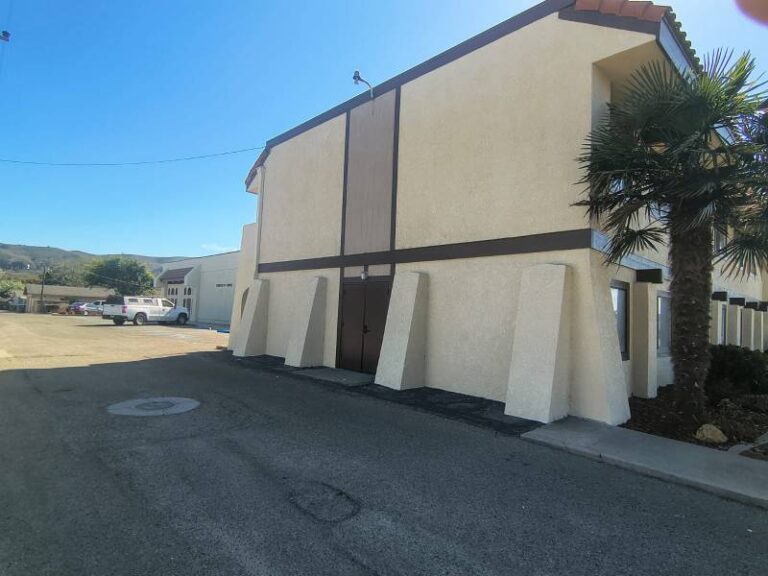 Freshly painted exterior of a two-story commercial building featuring beige stucco walls and dark brown trim.
